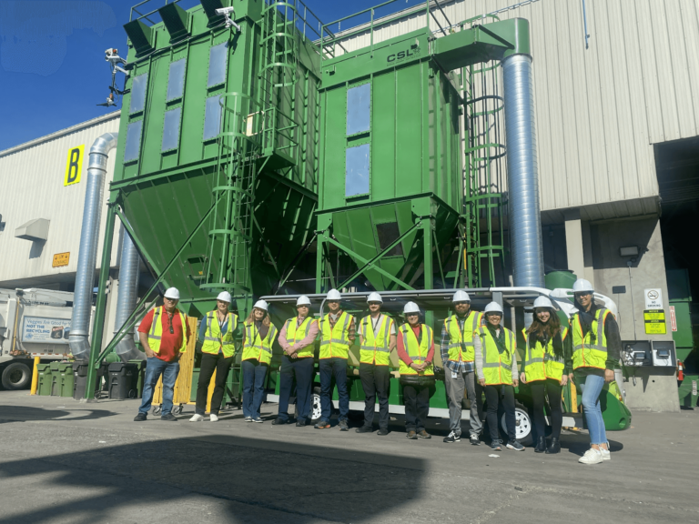 Group photo wear yellow construction vests and helmet in front of recycling sorting machine