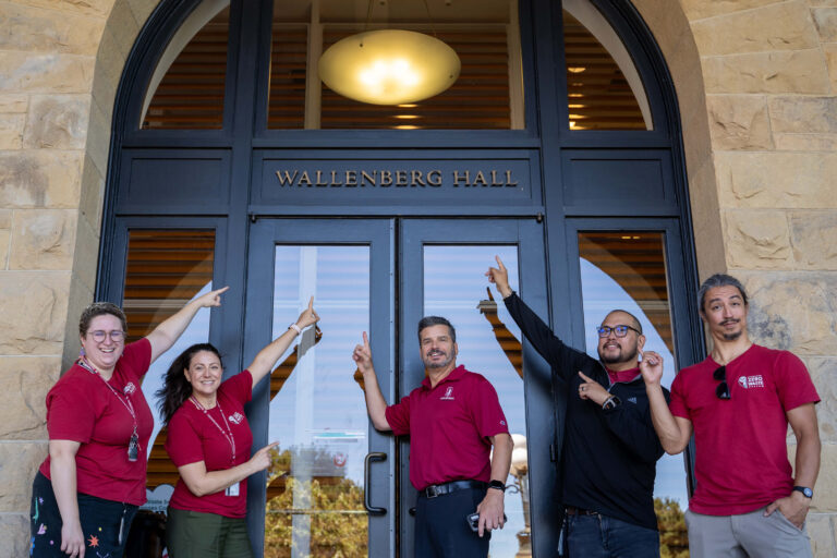 5 team members pointing to Wallenberg Hall