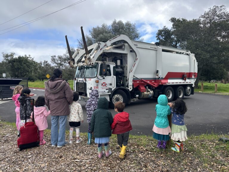 Young children gathered around garbage truck