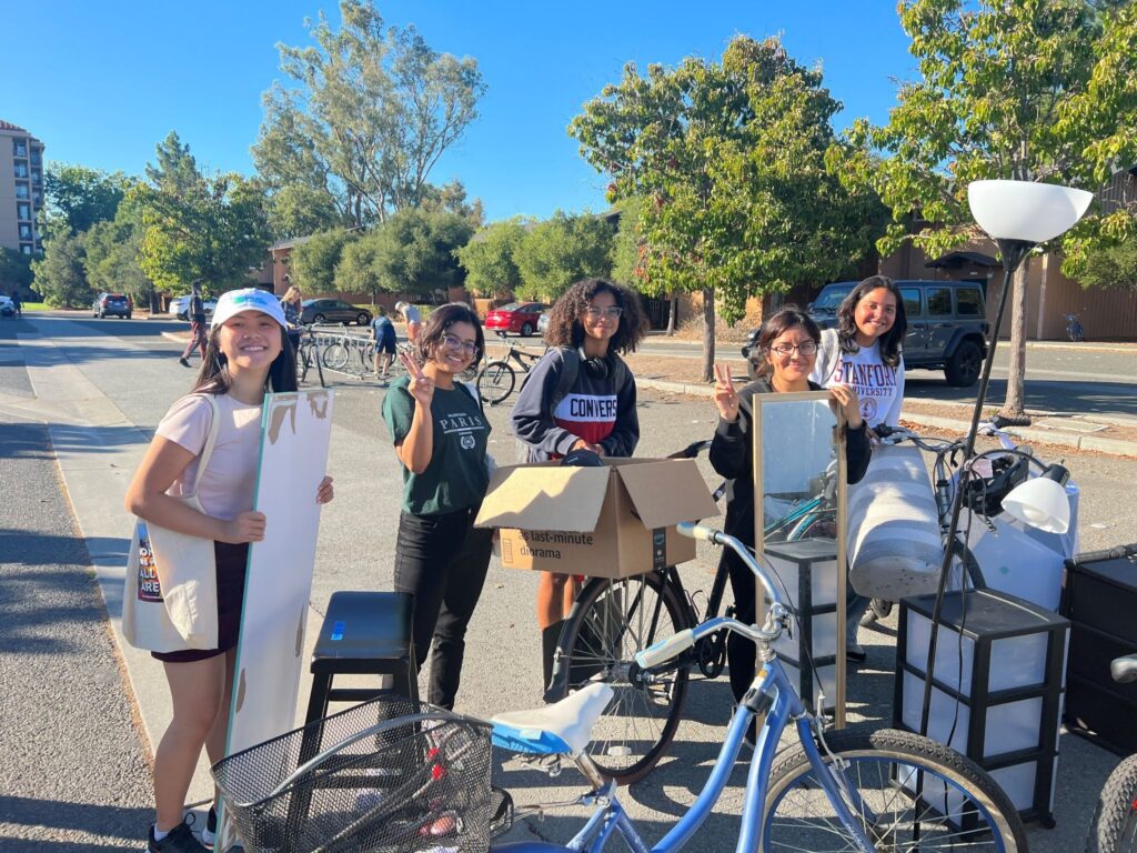 Students next to furniture and bikes they are donating for re-use