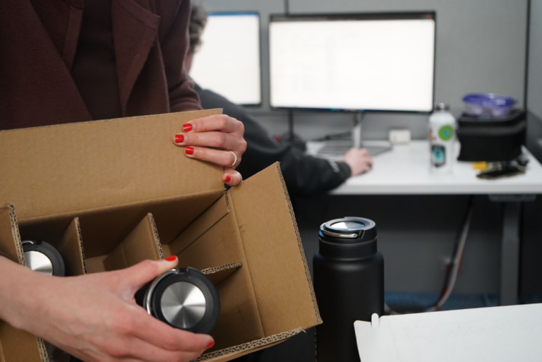 Staff member unboxing reusable/stainless steel water bottles from a cardboard box