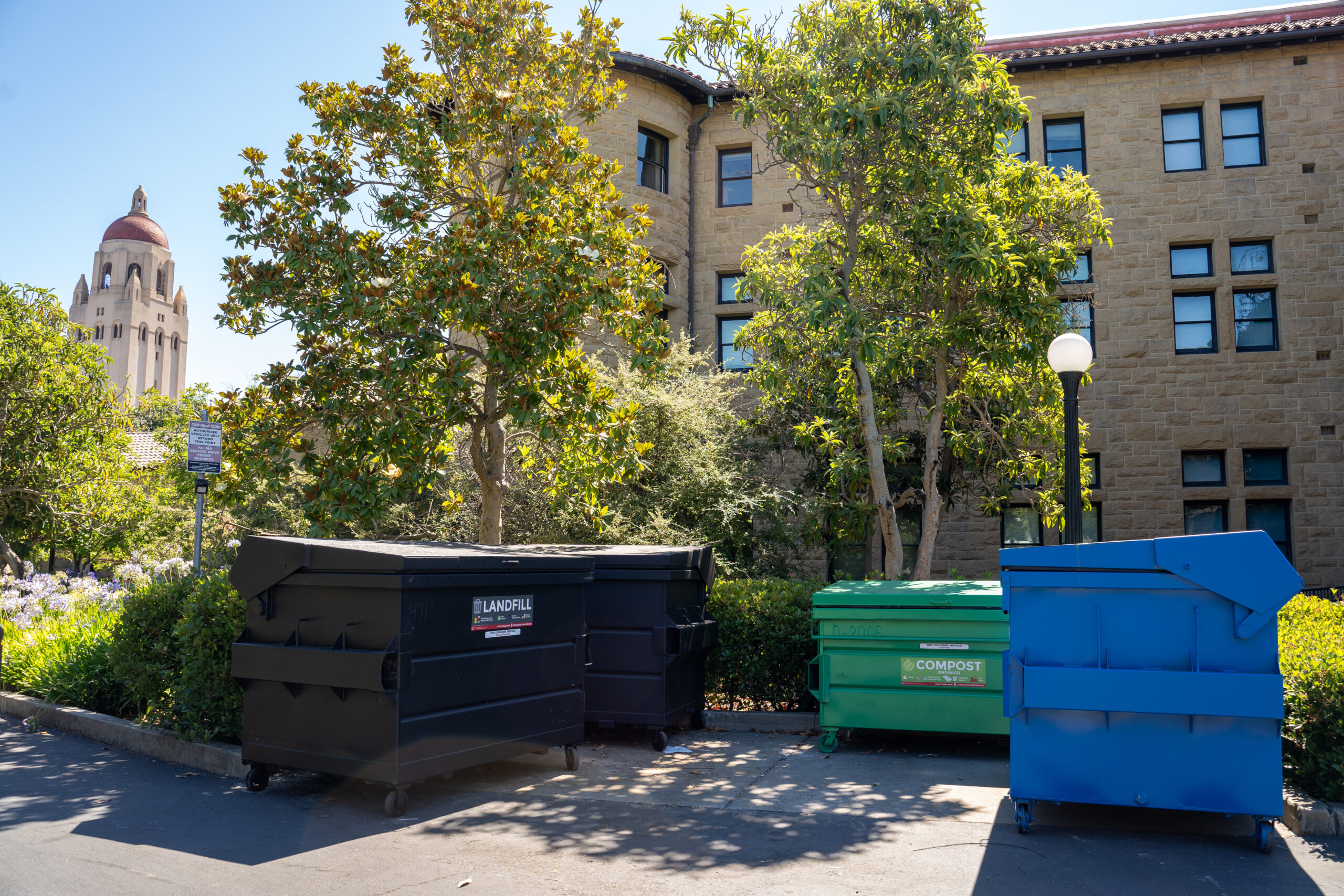 Three waste dumpsters with Hoover Tower in background