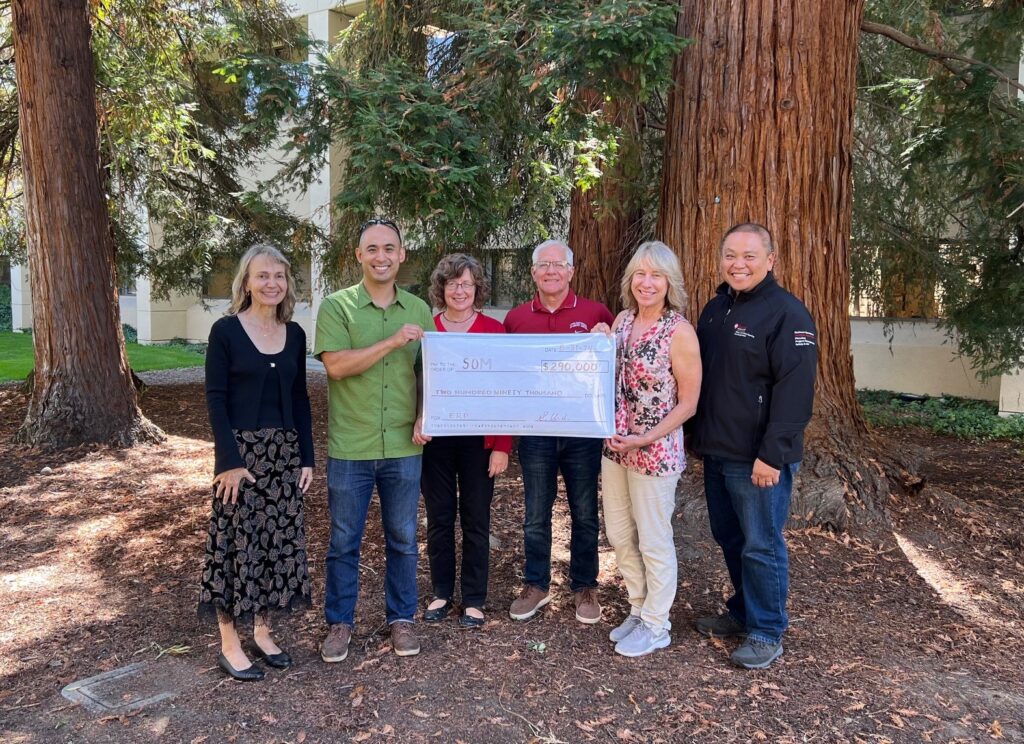 OFPM receiving a symbolic big check from FEM in 2024 outside in front of redwood trees
