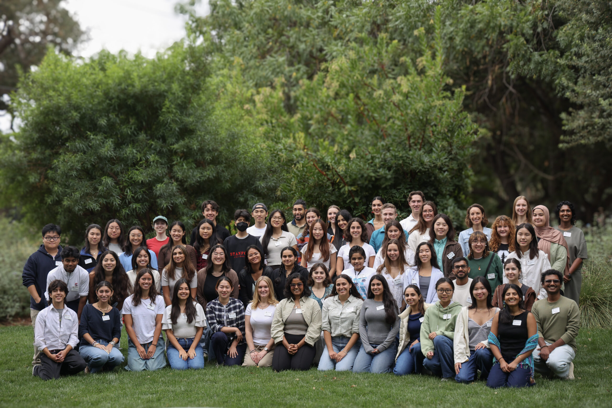 Photo of dozen of students with trees in the background