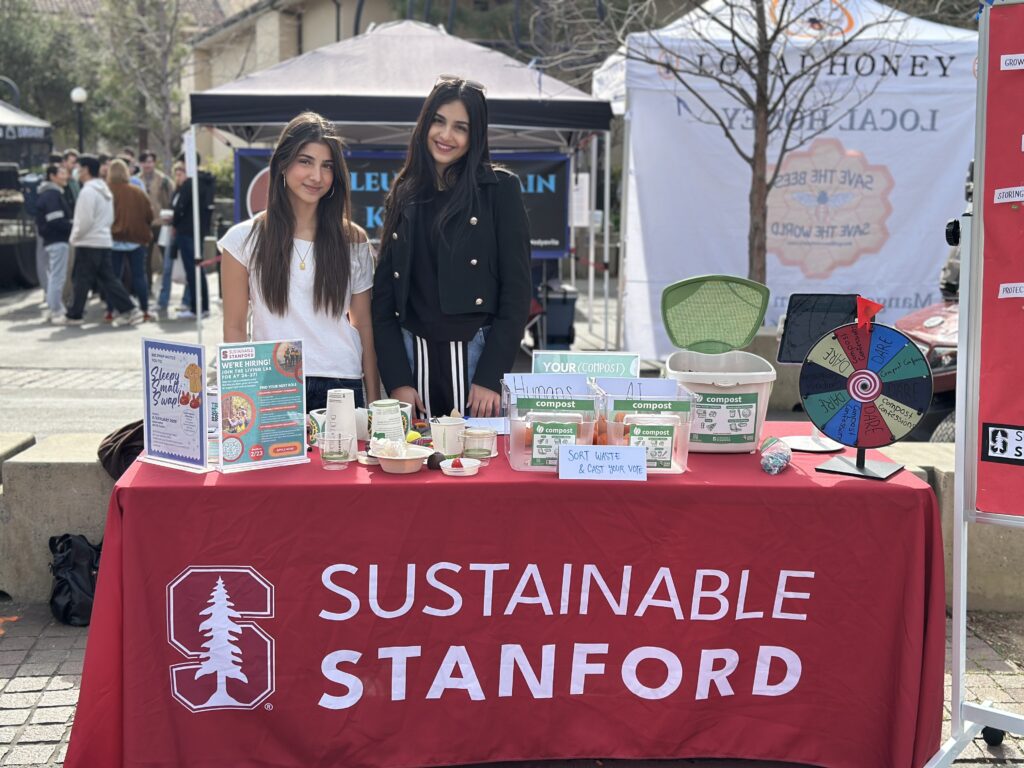 Two students standing behind Sustainable Stanford table