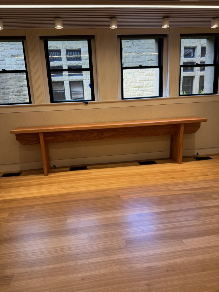 A bench inside a building with hard wood floor.