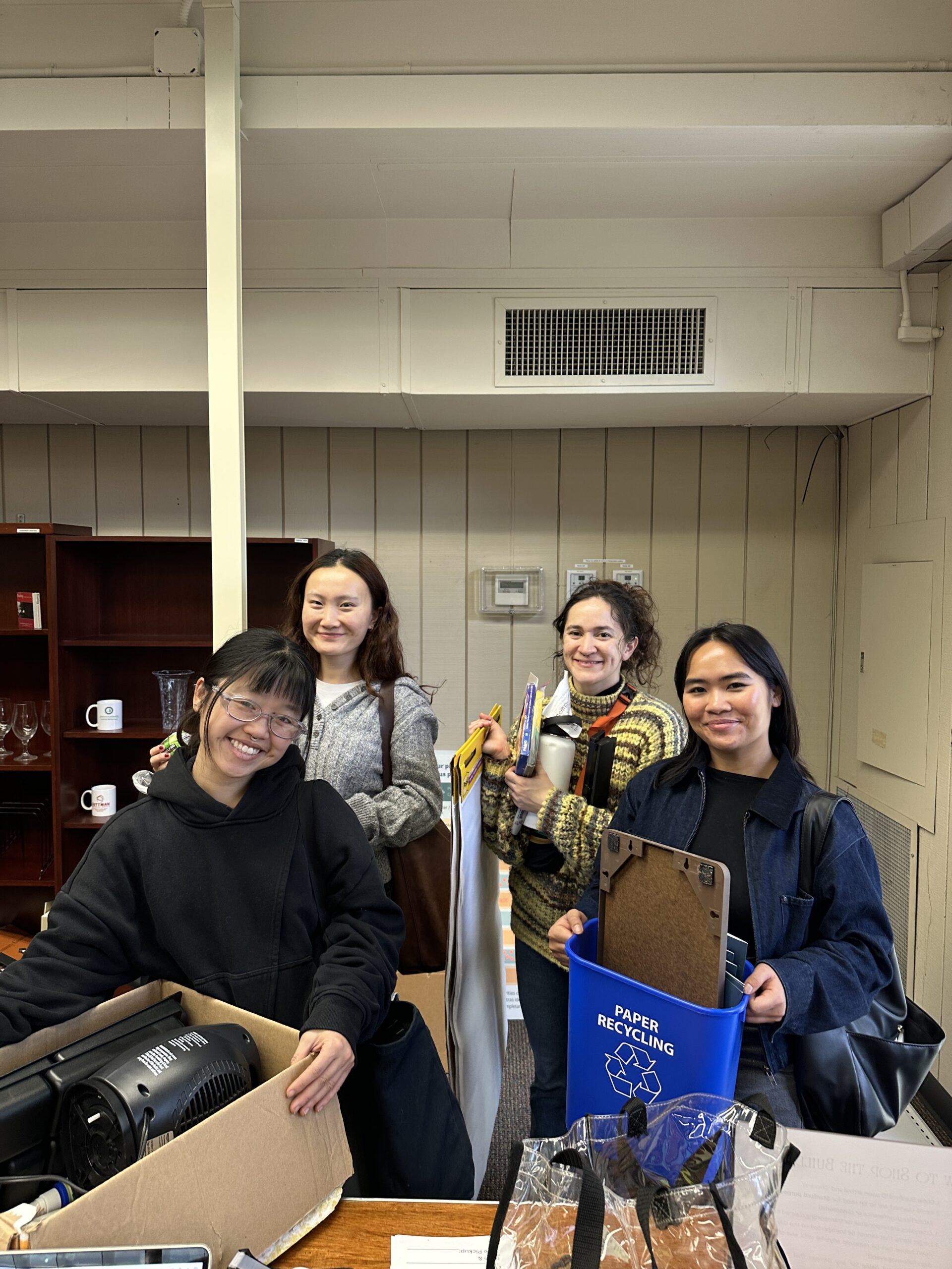 Four students holding various office supplies.