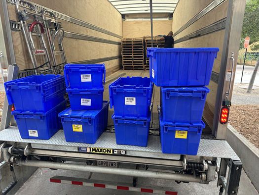The back of a semi truck with blue plastic boxes stacked up.